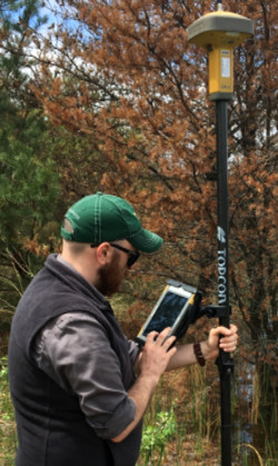 DNR staff holding a poled instrument called an RTK unit that measures lake elevation levels.