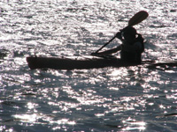 Person paddling a kayak on a glistening lake