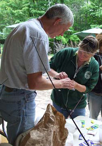 Two people work together to tie a hook on a fishing line during a casting activity at an instructor certification clinic.